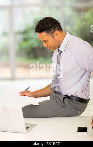 busy middle aged businessman reading report in office Stock Photo