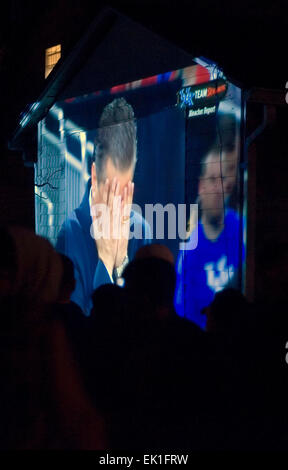 Wisconsin, USA. 05th Apr, 2015. University of Kentucky Wildcats fans at an outdoor party on State Street see Head Coach John Calipari covering his face with his hands in a live broadcast of their team's NCAA men's basketball game against the University of Wisconsin Badgers being projected onto the side of a house during the Final Four semifinal round of the NCAA men's basketball tournament late Saturday, April 4, 2015 in Lexington, KY, USA. UK lost the game 71-64 and ended its season with a 38-1 record, two wins short of a national title and undefeated perfect season. (Apex MediaWire Photo by  Stock Photo