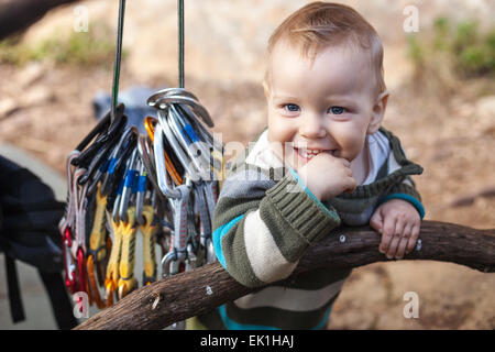 Child of rock climbers smiling while standing next to bundle of quickdraws Stock Photo