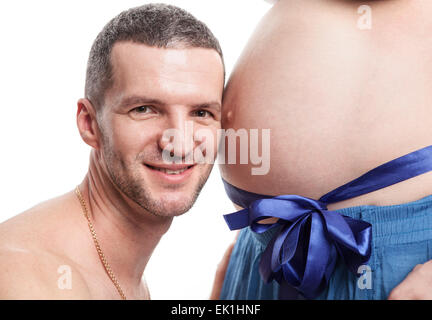 Cheerful young man listening to wife's pregnant tummy Stock Photo