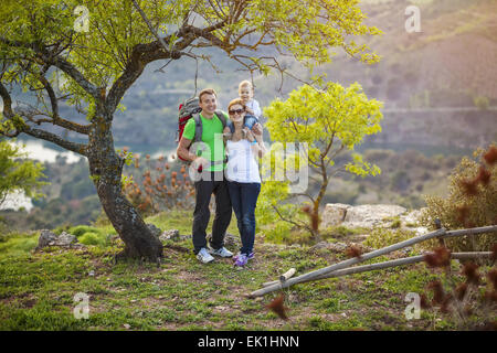 Young couple with toddler boy standing on cliff and enjoying valley view Stock Photo