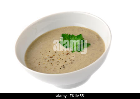 Mushroom cream soup in white bowl garnished with grated pepper and parsley leaf. Isolated Stock Photo