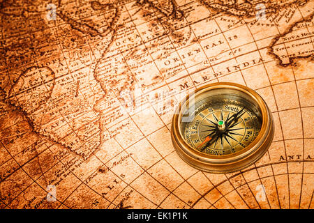 Vintage still life. Vintage compass lies on an ancient world map. Stock Photo