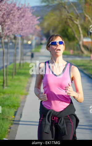 Young girl in a pink shirt jogging   on a sunny spring day Stock Photo