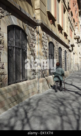 Elderly woman walking along street in sunshine, el Raval area of Barcelona, Catalonia, Spain Stock Photo