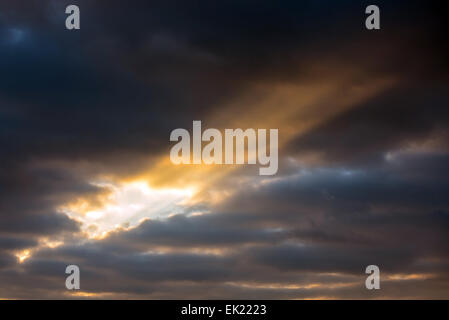 A beam of sun light breaks through heavy clouds during sunset in London. Stock Photo