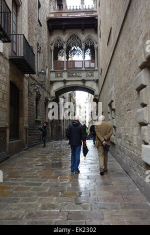 Two men walking along narrow street in Gothic Quarter of Barcelona on a rainy day Stock Photo