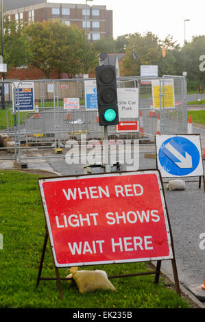 Roadworks with green traffic lights and a sign saying 'When red light shows wait here' Stock Photo