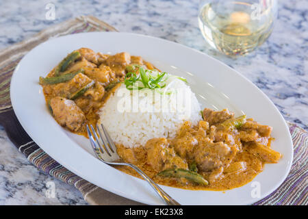 Chicken thighs and green bell peppers in panang curry sauce, served with rice Stock Photo