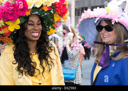 An African American woman and a Caucasian women walking together during the annual Easter Bonnet Parade on Manhatten's Fifth Ave Stock Photo
