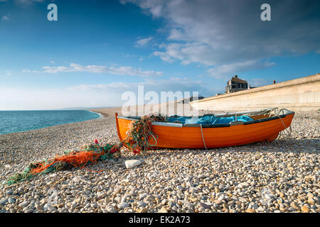 Orange fishing boat on Chesil Beach at Portland near Weymouth on the Jurassic Coast of Dorset Stock Photo