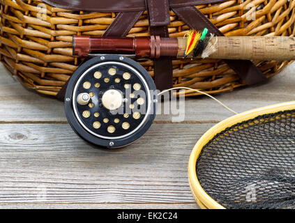 antique fly fishing reel, rod, landing net, creel and artificial flies on rustic wood. Layout in horizontal format. Stock Photo