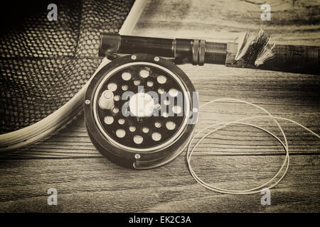 Vintage concept with grain of an antique fly fishing reel, rod, landing net and artificial flies on rustic wood. Close up with l Stock Photo