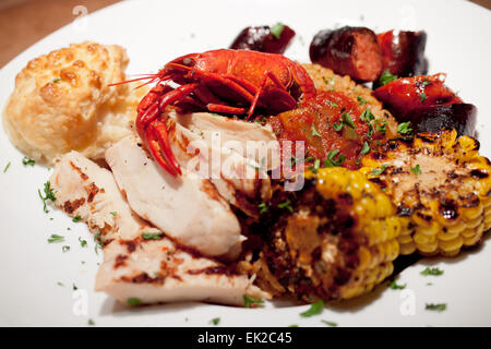 Cajun food: a plate of jambalaya with rice, a crawdad (crayfish), chicken, andouille sausage, and corn. Stock Photo