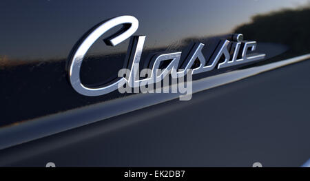 A closeup view of the word classic writting as a chrome emblem in a retro font set on a car painted in reflective black paint Stock Photo