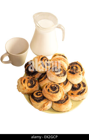 Cinnamon rolls and Bun with poppy seeds on a plate and small jugs of milk Stock Photo