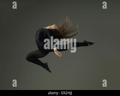 dancer performing high jump against grey background Stock Photo