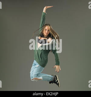 happy modern style dancer jumping against grey studio background Stock Photo