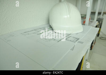 Rolls of architectural drawings and white construction helmet Stock Photo