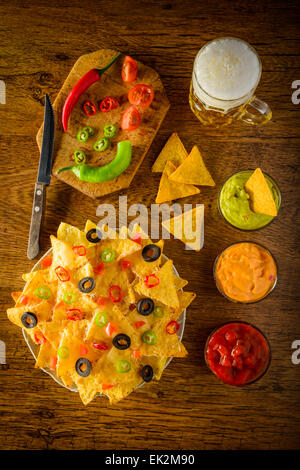 nachos on a plate with salsa, cheese and guacamole dip and beer mug Stock Photo
