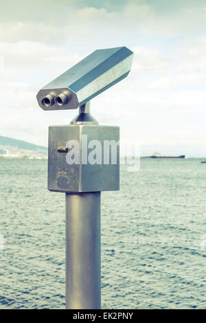Paid outdoor tourist telescope made of stainless steel on the sea coast Vintage stylized photo with old style green toned filter Stock Photo