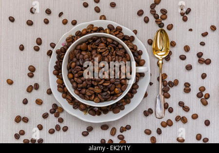 Cup and saucer filled with coffee beans and spoon Stock Photo