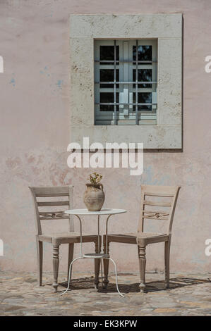 Two chairs and a table in a Mediterranean setting in the heat of the day Stock Photo