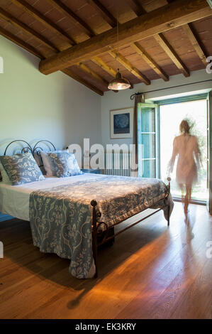 A lady walks towards the French doors of a double bedroom Stock Photo