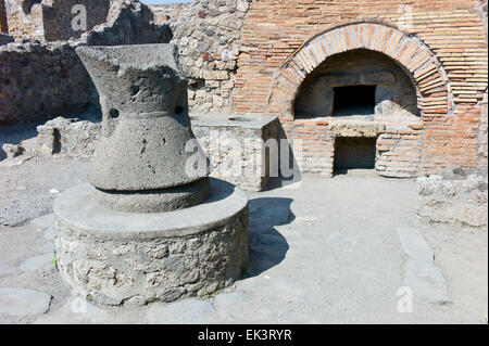 Millstone and oven at a bakery in the archaeological excavations of Roman Pompeii near Naples, Campania, Italy Stock Photo