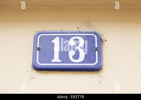 Number thirteen on a wall, detail of a number of information, odd number, superstition Stock Photo