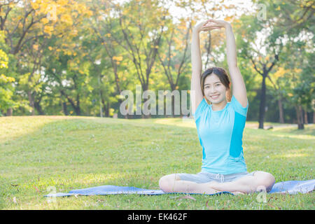 fitness, sport, training and lifestyle concept - Asian woman stretching outdoors Stock Photo