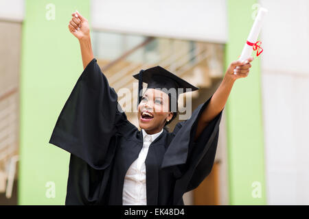 cheerful afro American female graduate standing in front of university building Stock Photo