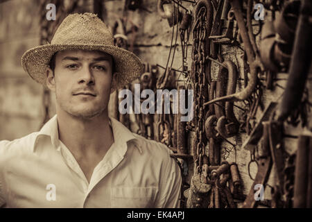 Farmer Portrait in front of a Wall Full with Old Rusty Tools Stock Photo