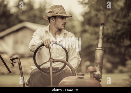 Young Farmer Driving a Red Old Vintage Tractor Stock Photo