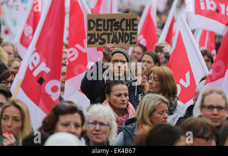 Hamburg, Germany. 7th Apr, 2015. A man is holding up a sign that reads 'Deutsche Zustaende' (German conditions) during a demonstration in Hamburg, Germany, 7 April 2015. More than 1000 employees working at nursery schools and other facilities providing social services have joined an all-day warning strike. German trade unions Verdi and GEW demand adjustments to wage brackets, which would ultimately increase the salaries of 240000 childcare assistants, pre-school teachers and social workers. PHOTO: AXEL HEIMKEN/dpa/Alamy Live News Stock Photo