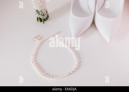 wedding pearl earrings and necklace close up with wedding shoes and bouquet background Stock Photo