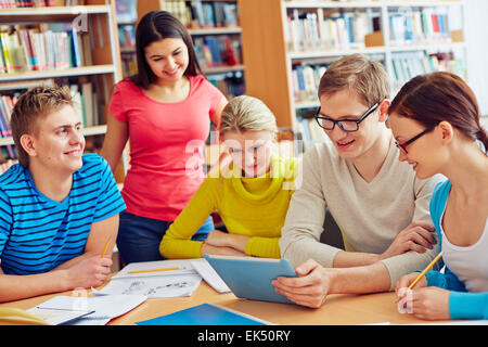 Group of friendly students discussing news in library Stock Photo
