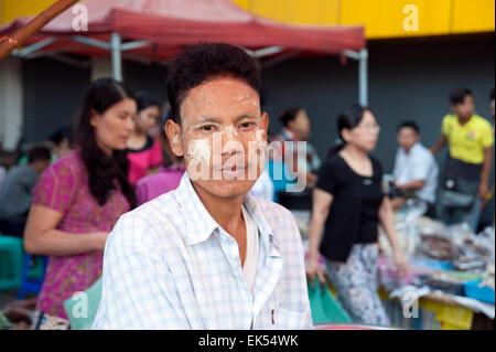 Portrait of a Burmese man face smeared with sandalwood paste at a busy Yangon street market Myanmar Stock Photo