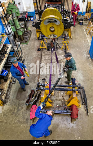 Engineers & volunteers expertly restore a tram to working condition - here using a gantry crane to inspect & move suspension Stock Photo