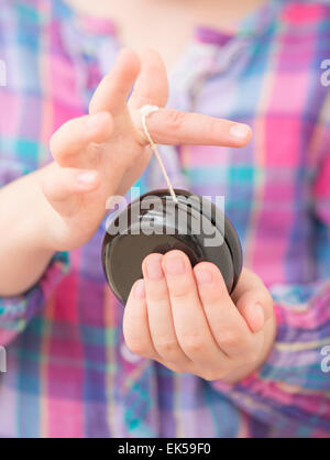 Close up of little girl (5 years) holding black wooden yo yo in her hands. Stock Photo