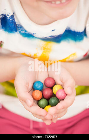 Little girl (5 years) holding colorful toy marbles in her hands. A moment of childhood fun and leisure games. Stock Photo