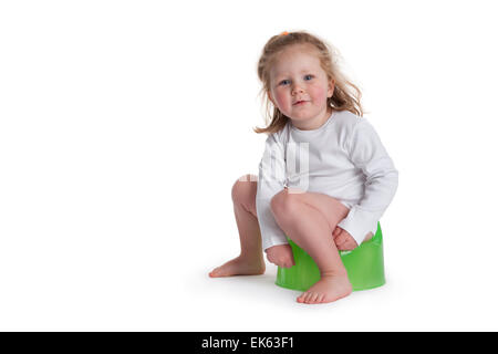 Three year old girl sitting on a potty on white background Stock Photo