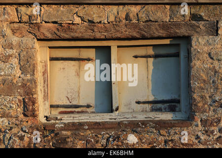 Old decaying window in barn with stone wall. Stock Photo