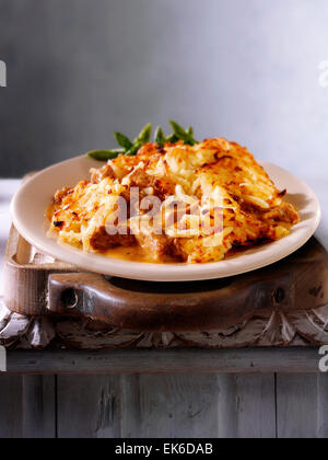 Cooked meal of beef casserole & potato rosti  served on a plate in a rustic table setting Stock Photo