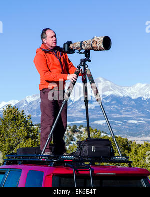 Professional photographer H. Mark Weidman shooting with a long telephoto lens from atop a Toyota 4Runner truck Stock Photo