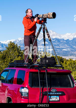 Professional photographer H. Mark Weidman shooting with a long telephoto lens from atop a Toyota 4Runner truck Stock Photo