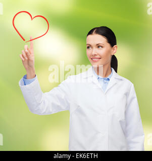 smiling female doctor pointing to heart Stock Photo