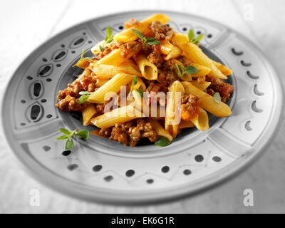 Fresh cooked pene and bolognese ragout served on a plate in a table setting. Serving suggestion Stock Photo