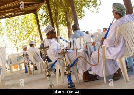 Omani men with Hubble Bubbles in a Coffee house on Shatti Al Qurum Beach, Muscat, Oman Stock Photo