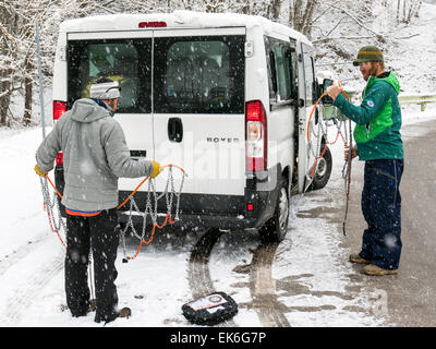 American skiers putting chains on a rental van, Dolomite Mountains, northern Italy Stock Photo